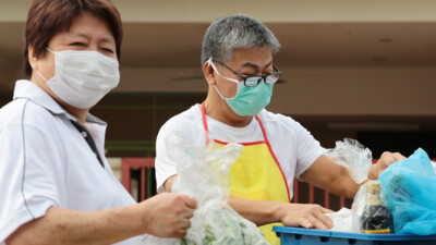 Two masked volunteers packing food supplies.