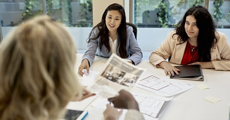 A real estate agent looking at commercial listings with two women.