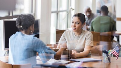 A woman speaking with a bank employee.