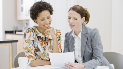 A businesswoman reviewing documents with a woman.