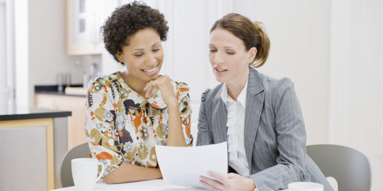A businesswoman reviewing documents with a woman.