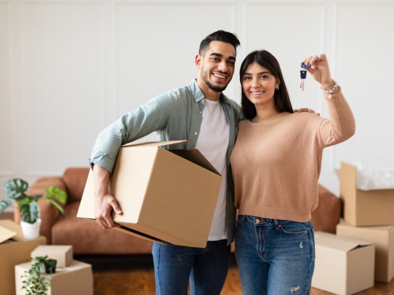 Man and woman with moving boxes and new house keys.
