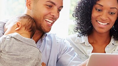 A man, a woman, and a baby looking at a computer.