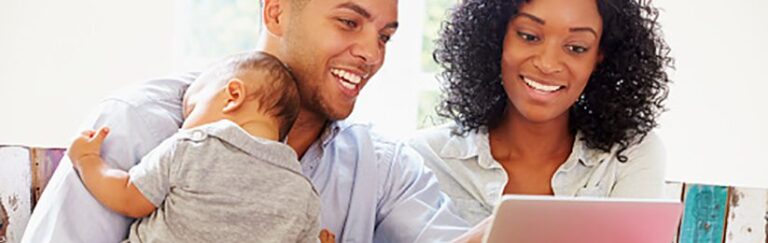 A man, a woman, and a baby looking at a computer.