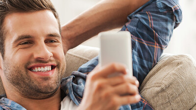 A man smiling at his cell phone.