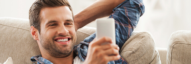 A man smiling at his cell phone.