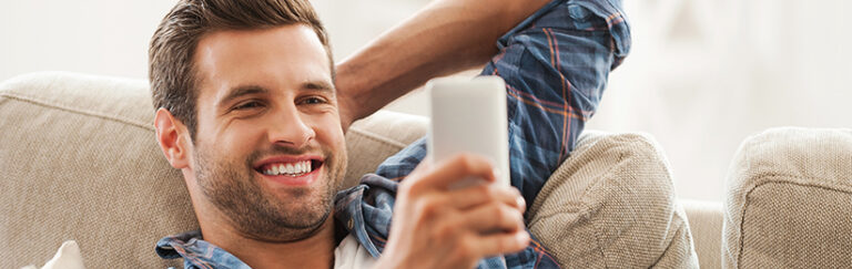 A man smiling at his cell phone.