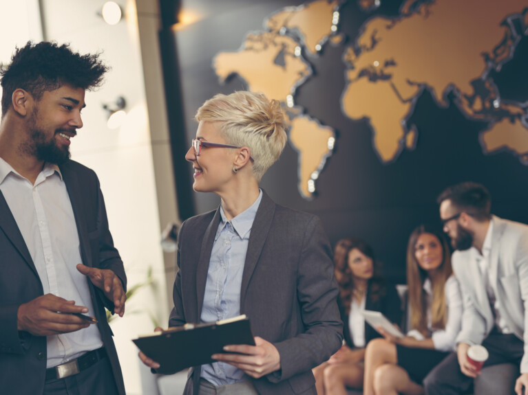 Businesspeople talking in front of a wall map.