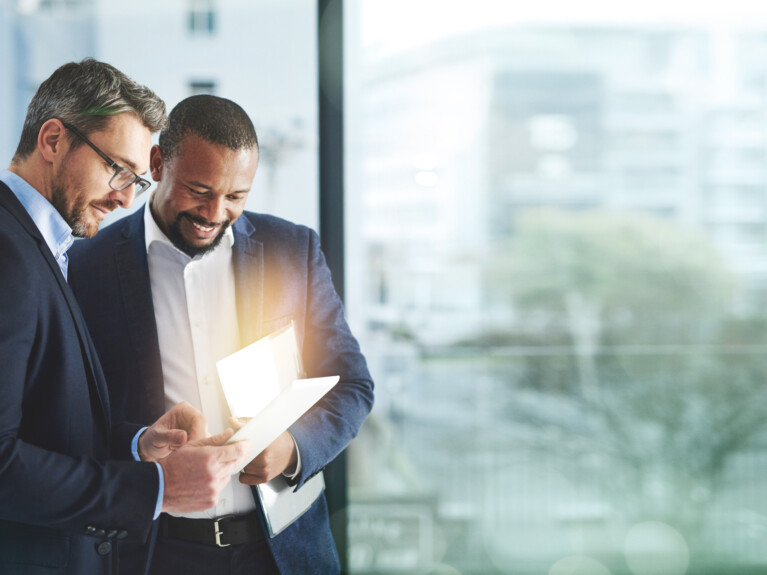 Two businessmen looking at a tablet.