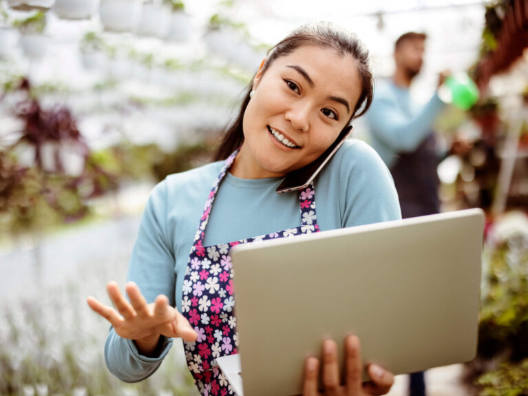 Businesswoman speaking on the phone and holding a laptop.