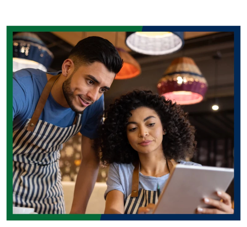 Two cafe owners looking at a tablet.