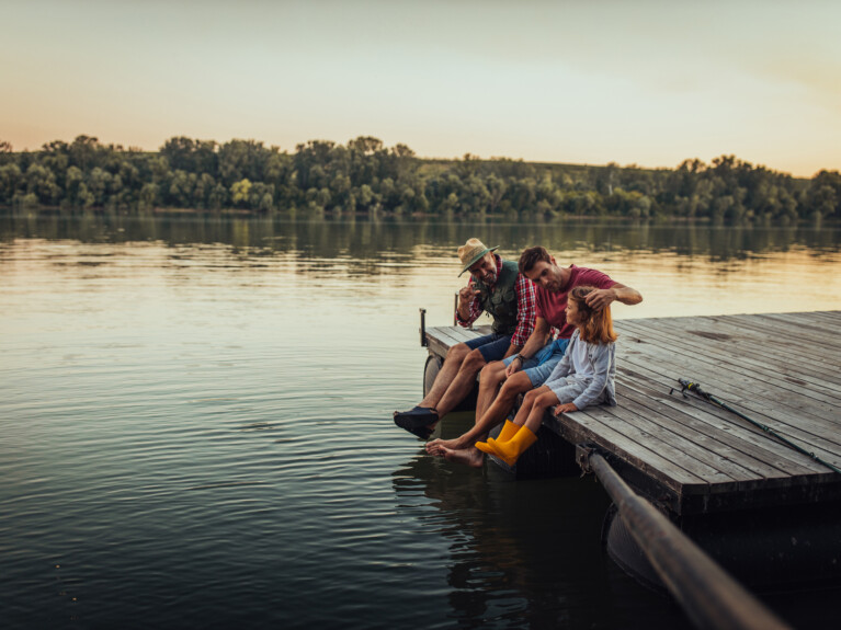 A family sitting on the end of a dock.