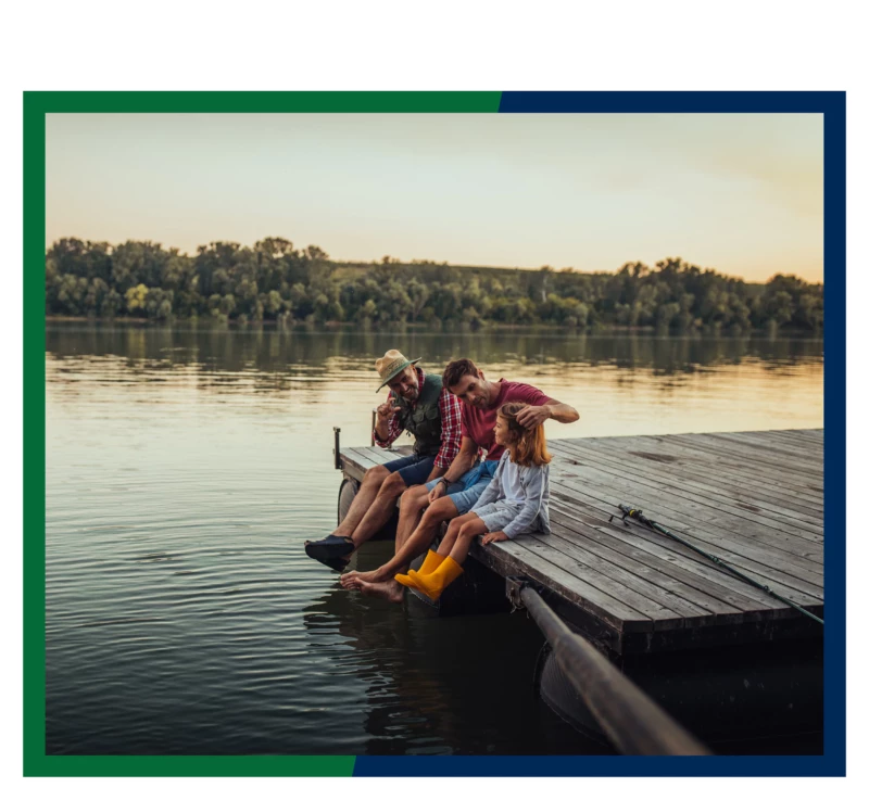 A family sitting on the end of a dock.