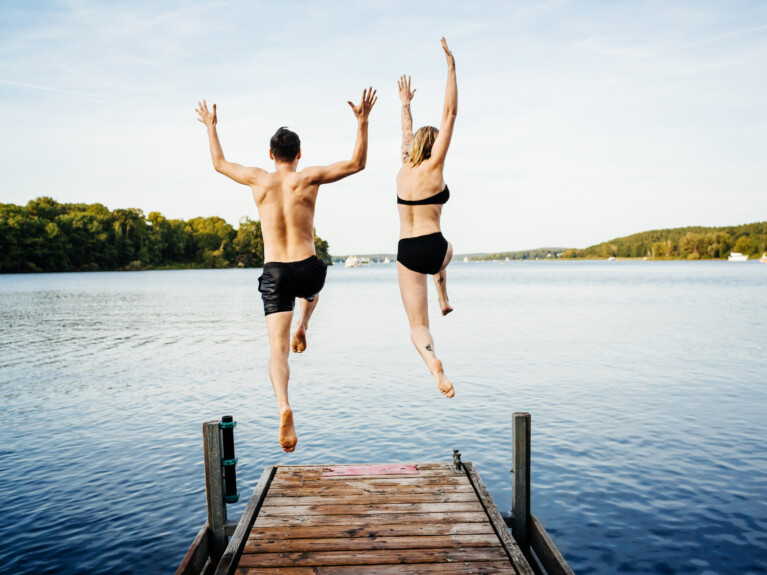 Two swimmers jumping off a dock.