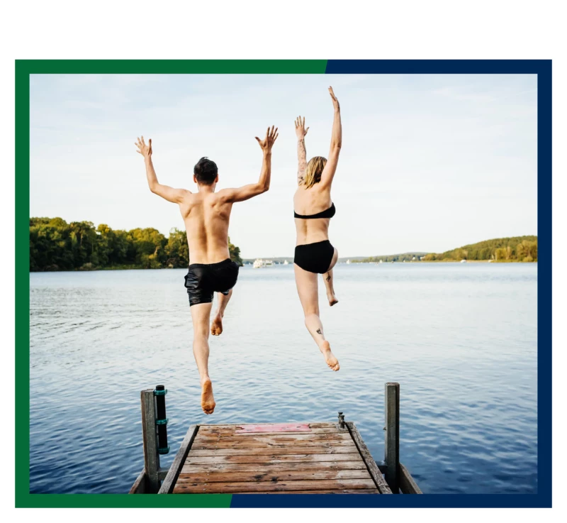 Two swimmers jumping off a dock.