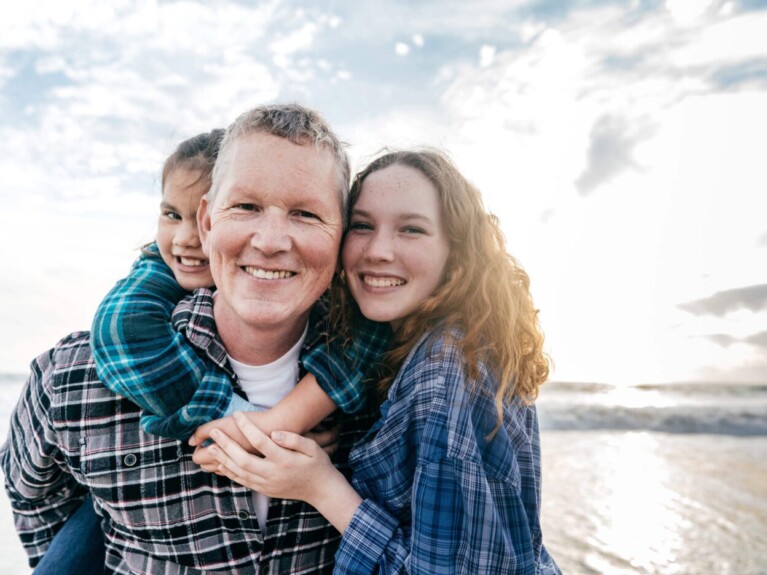 Family hugging and smiling at the beach.