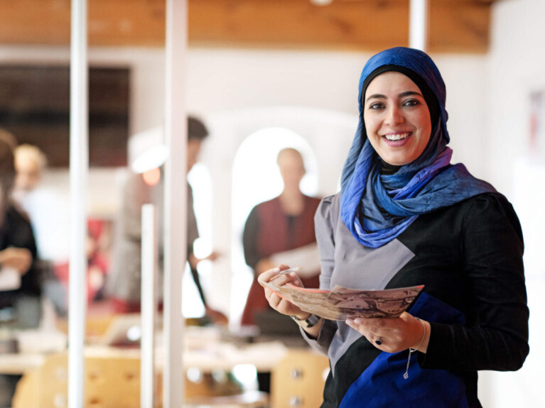 Woman holding fashion renderings.