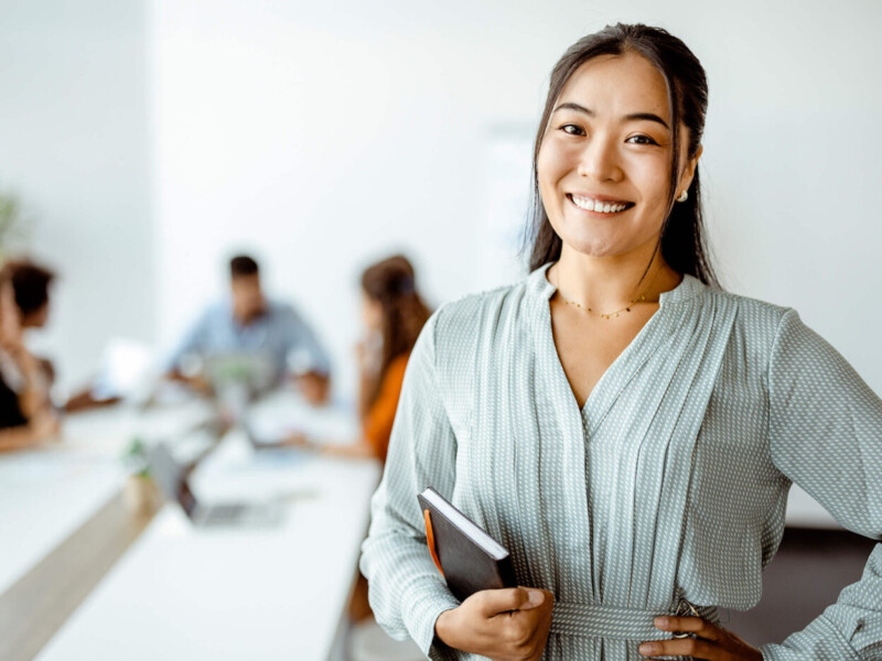 Businesswoman smiling with a notebook ready to conduct a wire transfer.