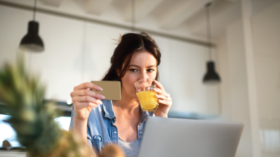 A woman looking at her credit card while drinking fruit juice.