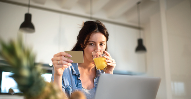 A woman looking at her credit card while drinking fruit juice.