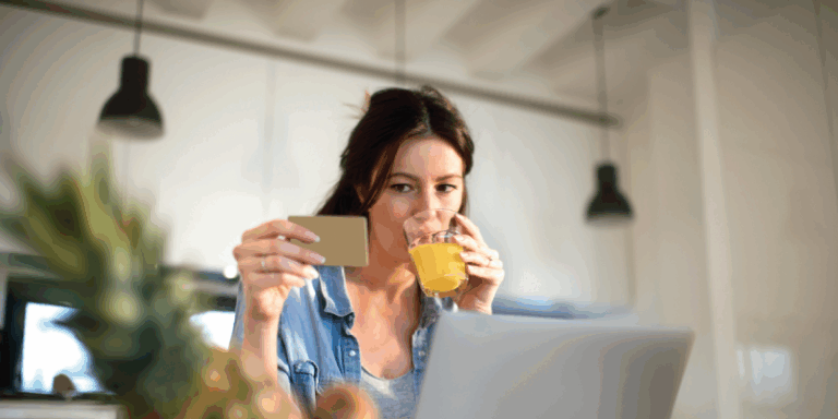 A woman looking at her credit card while drinking fruit juice.