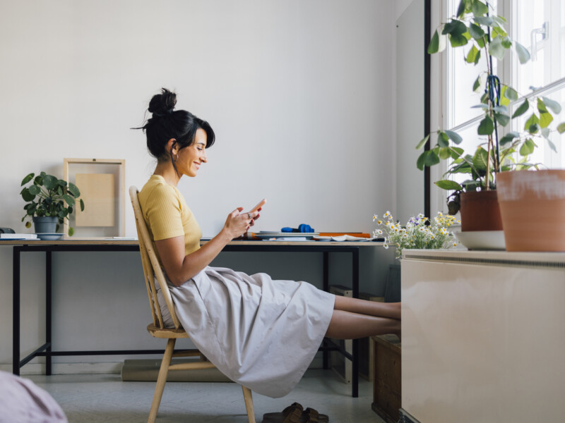 Women sitting at a desk looking at her phone.