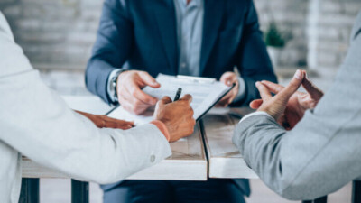 Shot of three business persons filling in paperwork in an office.
