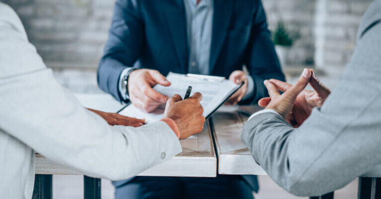 Shot of three business persons filling in paperwork in an office.