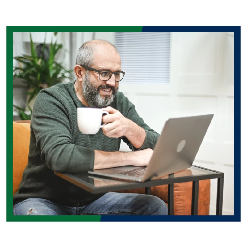 A man holding a mug and working at his laptop.