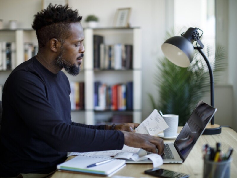 Man with documents in front of laptop.