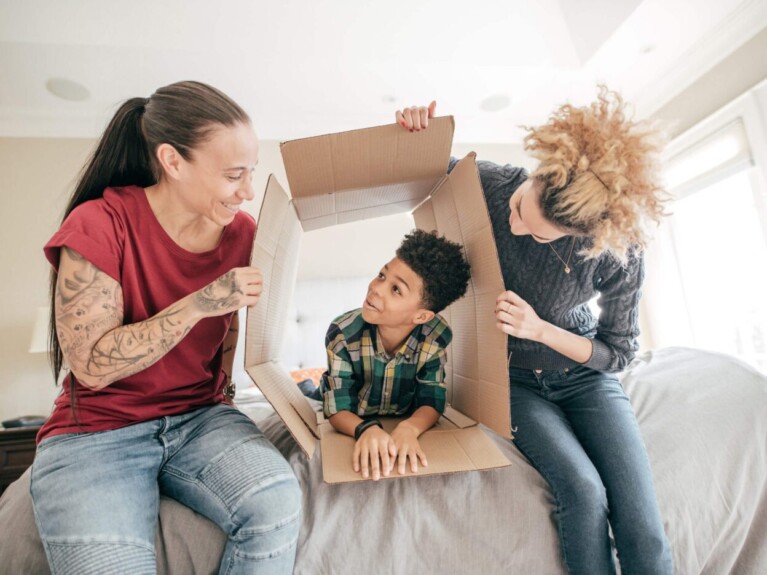 Two women and a child, playing with a moving box.