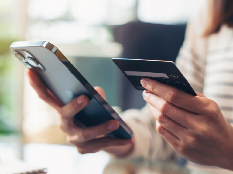 Hands holding a cell phone and a debit card.