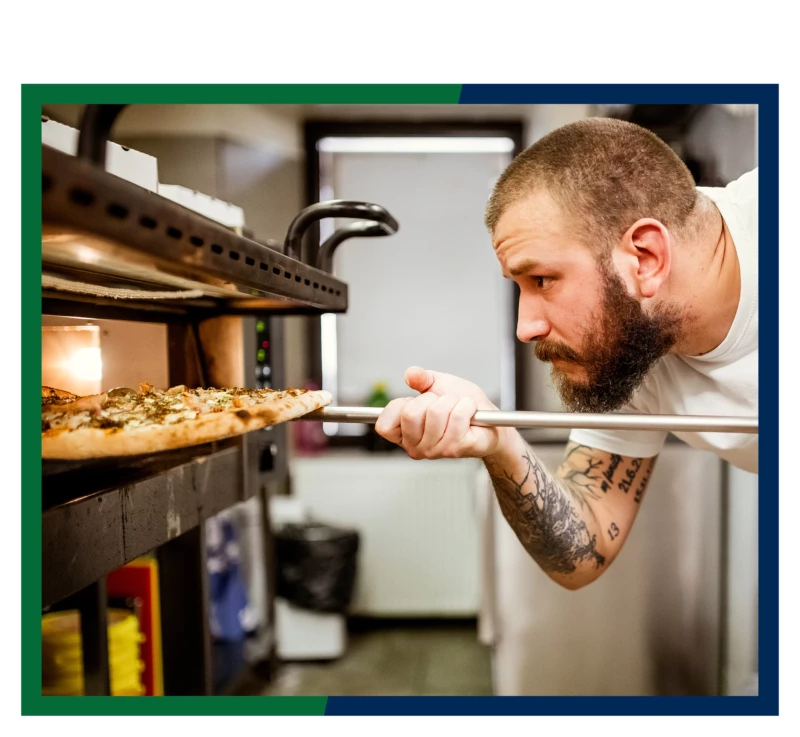 A chef putting a pizza into the oven.