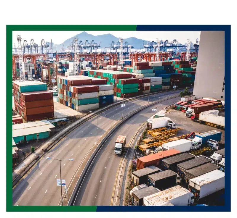 Shipping containers and trucks by a highway.