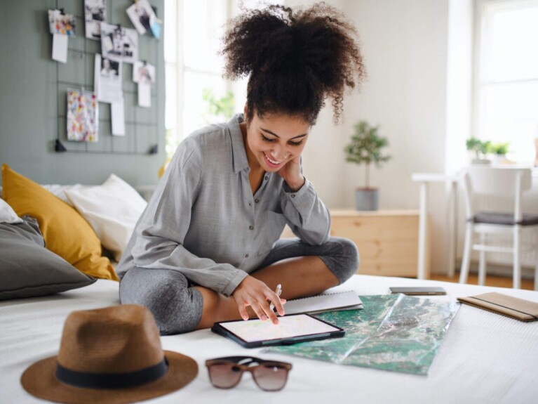 Woman sitting on bed looking at her core savings account on her tablet.