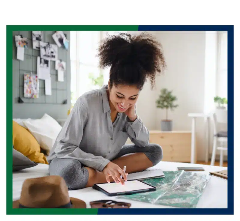 Woman sitting on bed looking at her core savings account on her tablet.