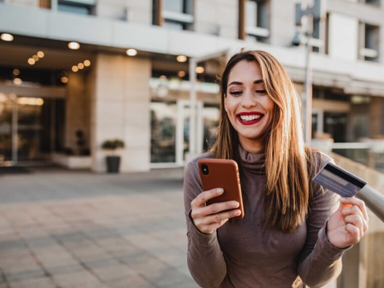 Choose the Credit Card That’s Right for You | A woman holding a credit card and a cell phone.