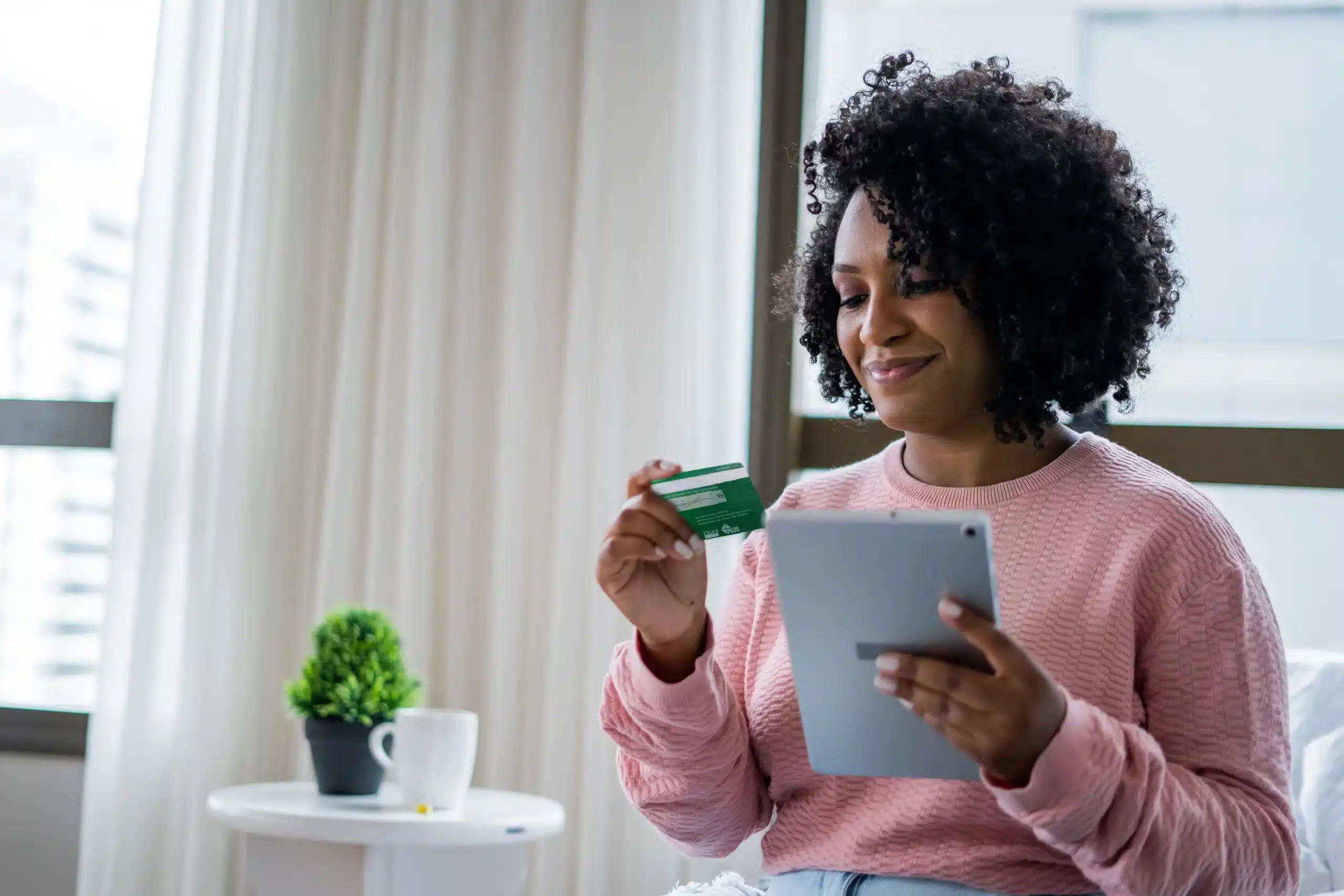 A woman holding a tablet and a debit card.