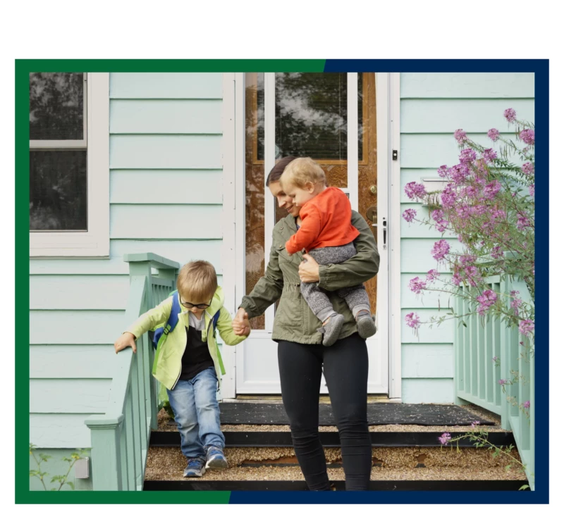 A mother and two small children walking down the front steps of their home.